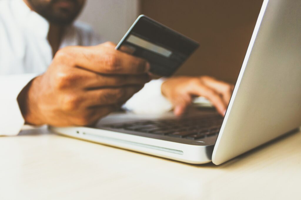 Pessoa comprando pela internet, segurando cartão de crédito
