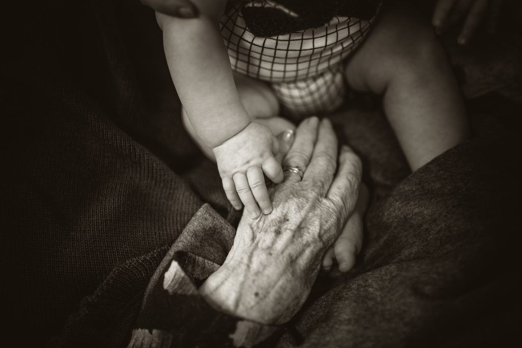 Bebê segurando a mão de ancião